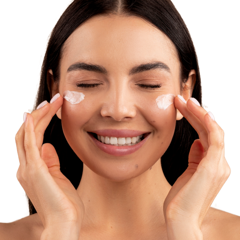 Mujer aplicando crema facial con una sonrisa, representando el rejuvenecimiento facial con tratamiento de flacidez para una piel más firme y tonificada.