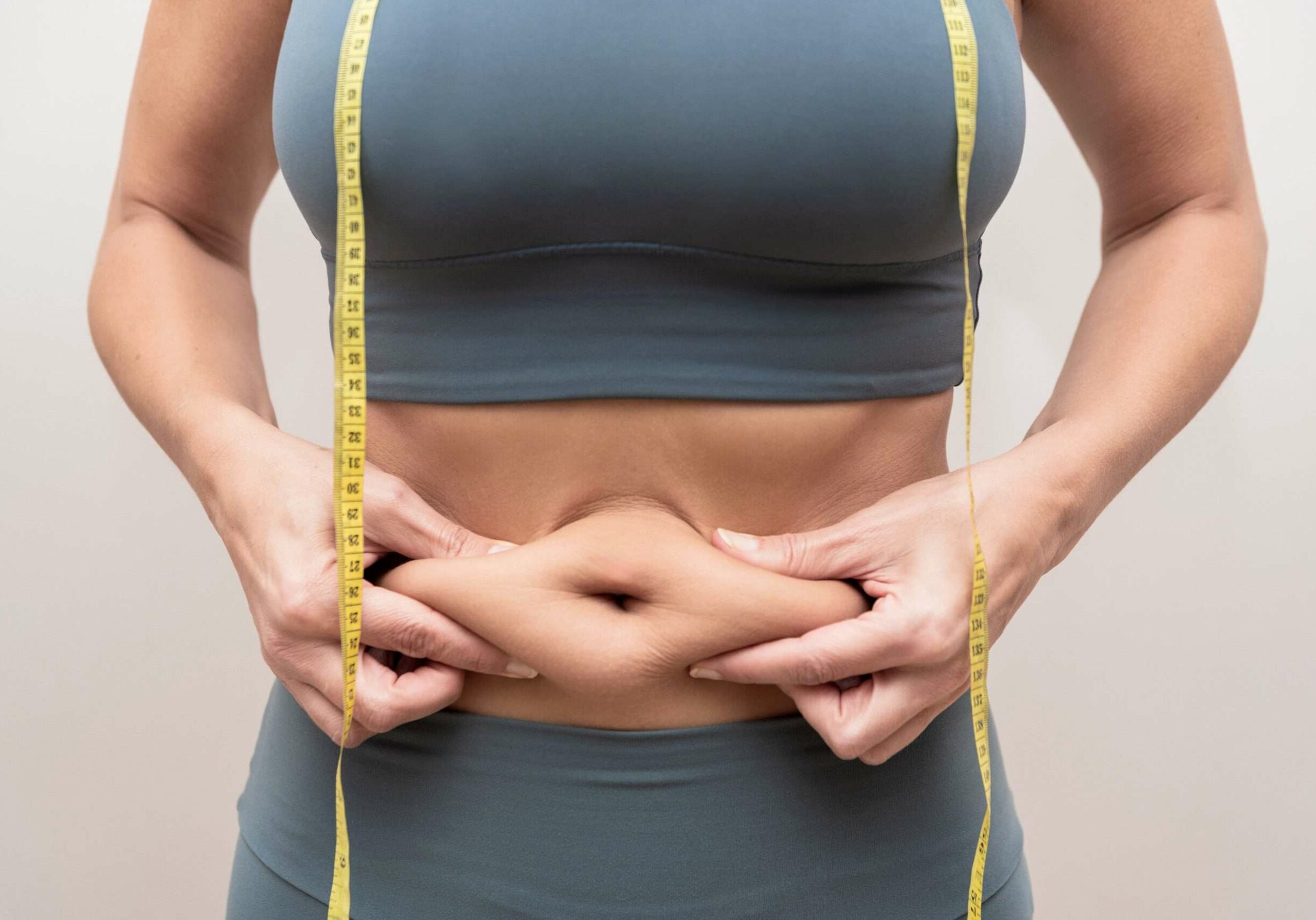 close-up-of-woman-pinching-belly-fat-with-a-yellow-2025-03-13-01-30-08-utc-min